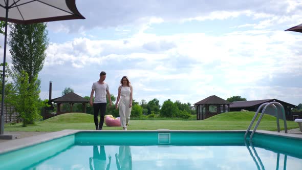 Cheerful Loving Carefree Couple Walking in Slow Motion to Swimming Pool at Tourist Resort Outdoors