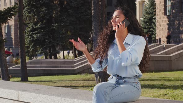 Attractive Happy Young Girl Brunette Woman Talking on Mobile Phone Answers Call Sitting in City