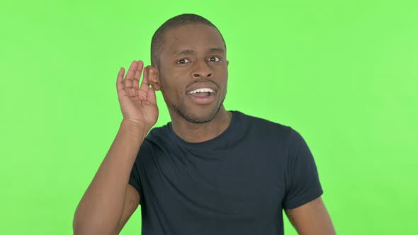 Young African Man Listening Secret on Green Background