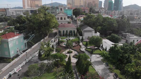 Tilt reveal shot of Taipa skyline in Macau with park and church in foreground and casino hotel in ba