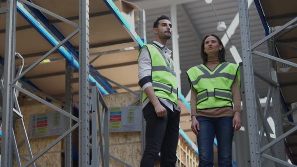 Focused Employees Looking Around Standing in Warehouse Pointing and Talking