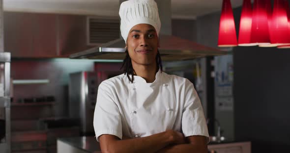 Mixed race male chef standing in kitchen looking at camera and smiling