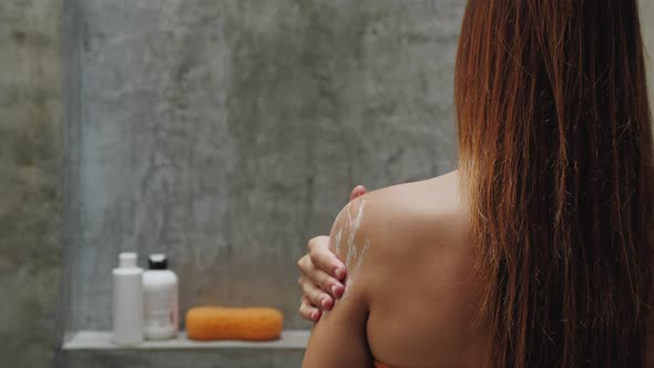 Closeup of Woman Arm Moisturizing and Massaging Her Shoulder on Blue Background Relaxation and Skin