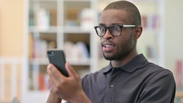 Portrait of Excited Young African Man Celebrating on Smartphone