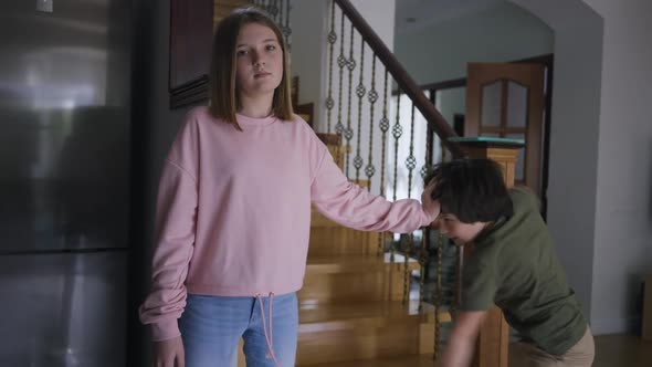 Portrait of Caucasian Teenage Girl Ignoring Little Boy Fighting with Sibling