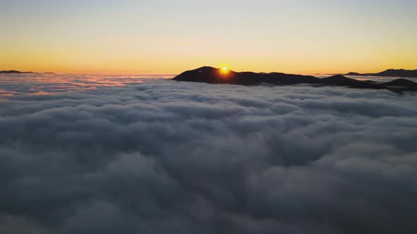 Aerial view of vibrant sunrise over white dense fog with distant dark Carpathian mountains