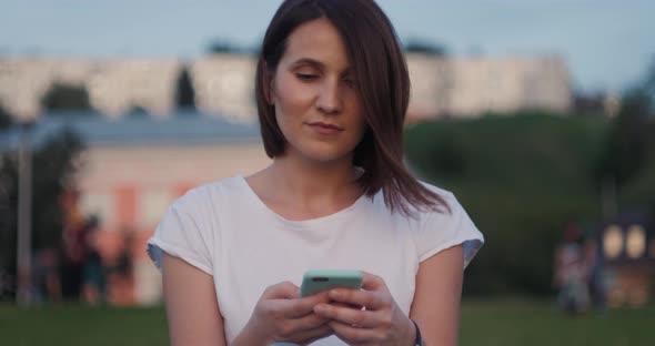 Beautiful Young Woman Typing on Phone Outdoors