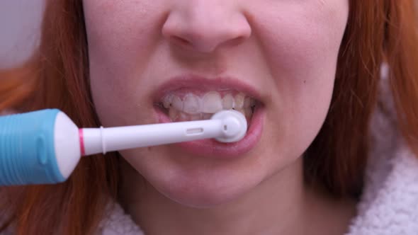 Close Up Of Woman Brushing Teeth With Electric Toothbrush