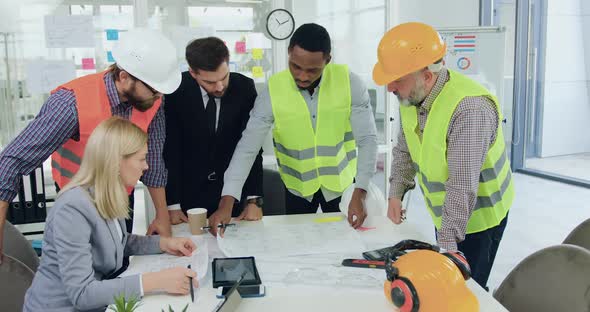 Team of Engineers of Building Company Analyzing Construction drawing