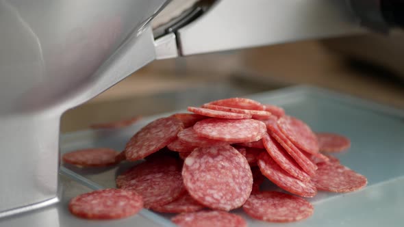 Slicing a pepperoni sausage. A meat slicer at work