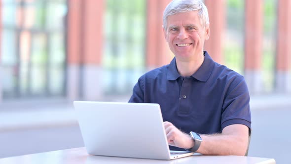 Outdoor Middle Aged Businessman Smiling at Camera While Using Laptop
