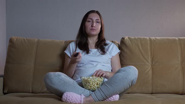 Lady Eats Chips and Switches Channels Using Remote Control