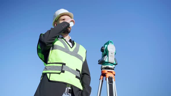 Medium Shot Portrait of Confident Engineer Standing at Background of Clear Blue Sky Drinking Coffee