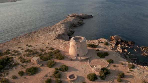 Flying away from pirate tower in Ibiza, aerial view of lookout tower.