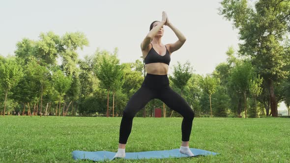 Young Fit Woman Practicing Yoga in Park at Sunset