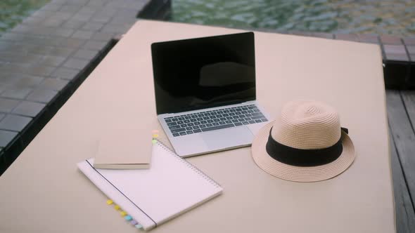 summer travel concept laptop summer hat and paper note book arrange on pool bench