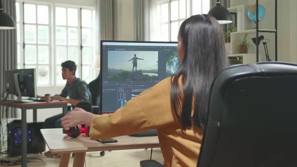 Back View Of Asian Female Video Editor Start Works With Footage And Sound On Her Personal Computer