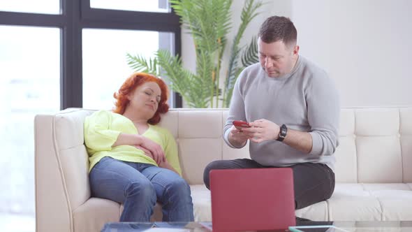 Wide Shot Portrait of Caucasian Husband Checking Messages in Wife Smartphone and Waking Up Cheating