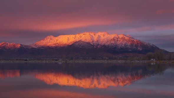 Snow capped Timpanogos Mountain glowing at sunset reflecting in Utah Lake