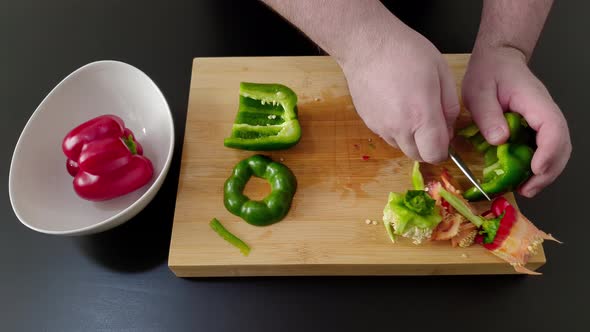 Hand of chef cuts and cleans green pepper. Close up and high angle