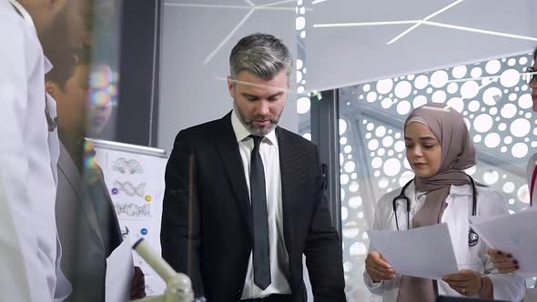 Multiethnic Male and Female Doctors Shaking Hands with One Another After Joint Symposium in Hospital