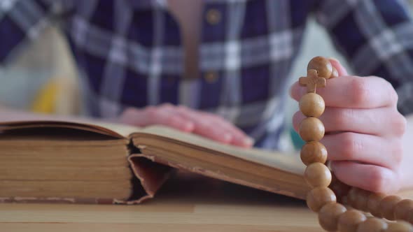 Close Up of a Rosary in the Hands of a Woman Reading the Bible