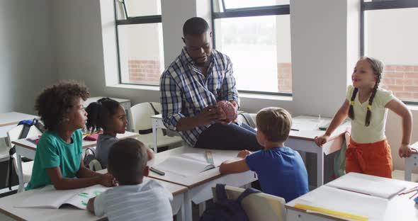 Video of happy african american male teacher and class of diverse pupils during biology lesson