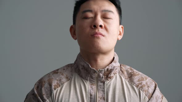 Sad military Asian man taking a deep breath