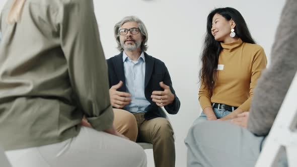 Portrait of People Holding Hands Talking and Smiling During Group Therapy Meeting Indoors