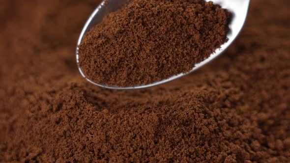 Instant coffee powder. Brown morning fragrant drink granules in a spoon. Falling in slow motion