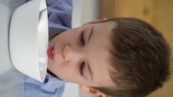 Small Hungry Boy Eating Tasting Sweet Corn Flakes with Milk at Morning