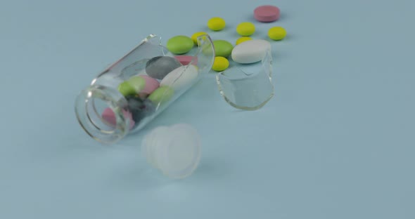 Broken Glass Jar with Many Different Pills and Drugs Spinning on Blue Background