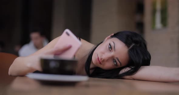 Tired Woman Using Smartphone Lying on a Table