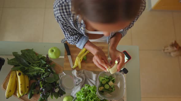 Young Sportswoman Putting Washed Greenery on Table and Cooking Smoothie