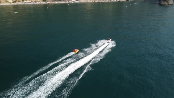 Happy People are Going to Swim on an Air Mattress Behind a Jet Ski