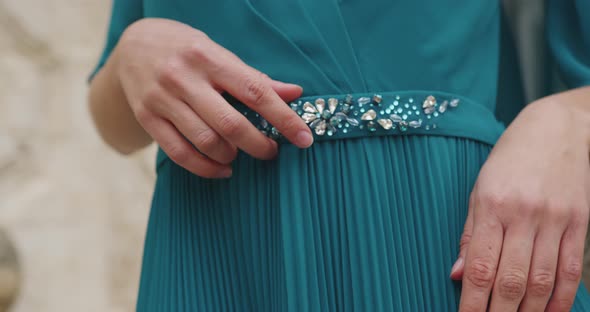 beautiful female girl's hand touches belt on the dress with jewelry with fingers