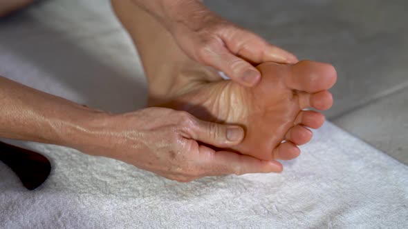 Extreme closeup of mature woman massaging her foot with her hands.