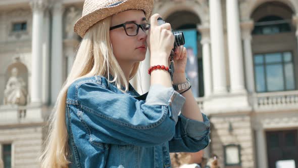 Young woman tourist taking a picture on retro camera of a city on vacation