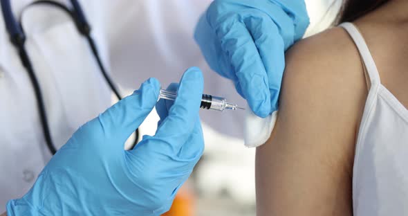 Doctor in Gloves Holds Syringe with Vaccine and Injects Patient in Shoulde