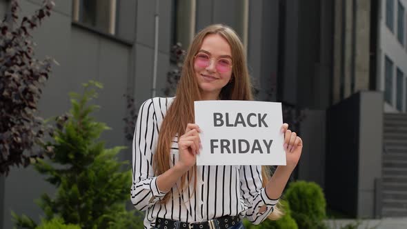 Joyful Teen Girl Showing Black Friday Inscription, Smiling, Looking Satisfied with Low Prices