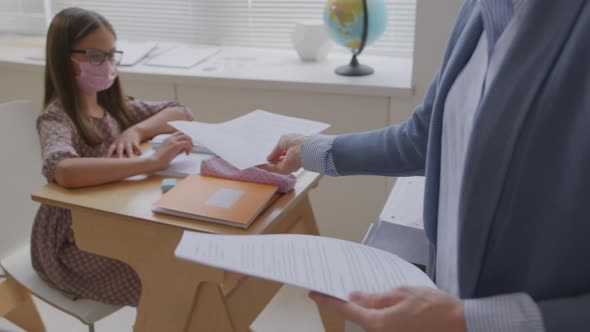 Teacher Handing Tests to Children in Face Masks