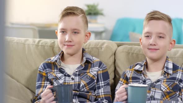 10-year-old Caucasian Twin Brothers Rubbing Ear in Unison alt