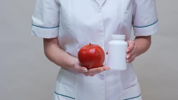 Nutritionist Doctor Healthy Lifestyle Concept - Holding Organic Red Apple and Jar of Vitamin Pills