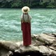 Young vintage woman in dress and straw boater hat stand near rippling mountain river, back view - VideoHive Item for Sale