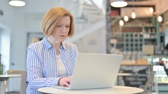 Loss on Laptop By Creative Old Woman in Cafe