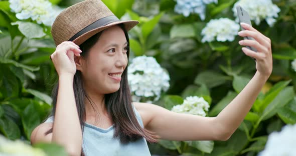 Young Woman taking selife on cellphone in Hydrangea farm 