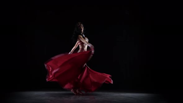 Traditional Oriental Belly Dancer Girl Dancing in Chiffon Red Dress, Black Background