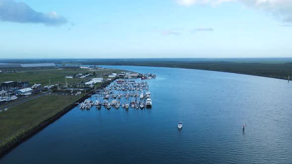 A high revealing drone view of multiple boats docked in a protected harbor located in the town of Ba