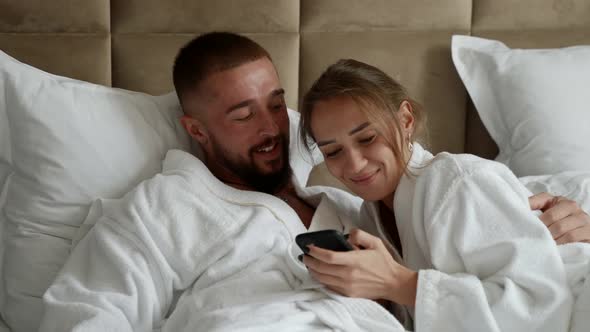 Lovers are Resting in Hotel Room and Watching Video in Smartphone