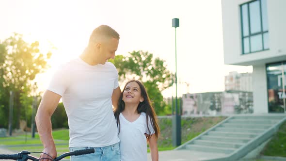 Dad and Daughter Walk Around Their Area at Sunset